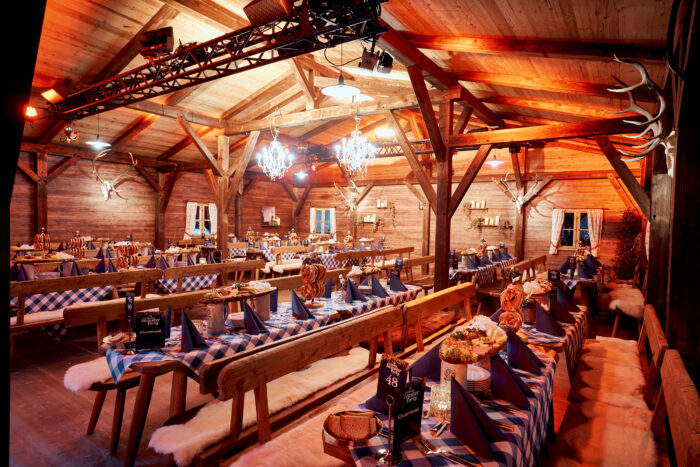 Rustikal dekorierte Event-Location im Hüttenstil mit festlich gedeckten Tischen und bayerischer Atmosphäre.