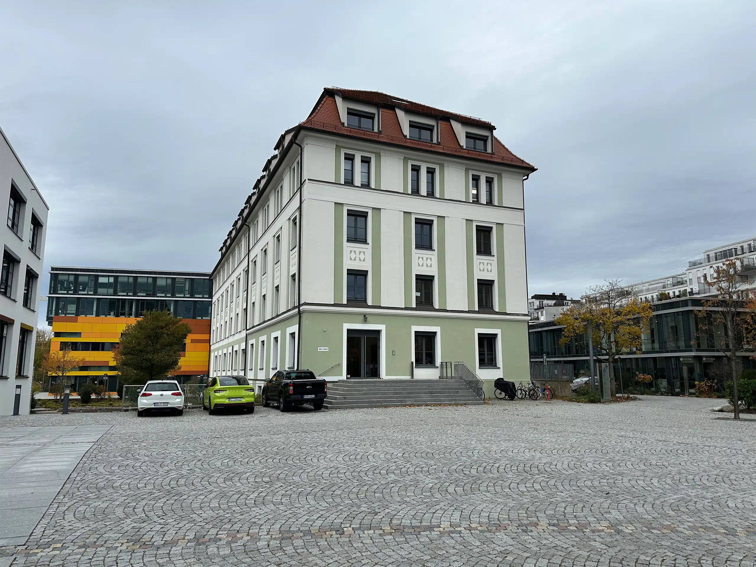 Außenansicht des Innsiders Media Büros in München mit parkenden Autos davor.